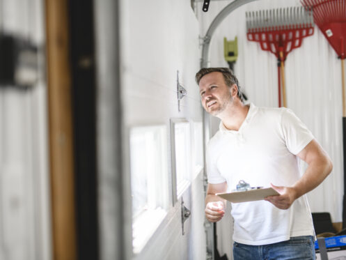 Garage door technician inspecting a garage door to give a quote for repair or replacement.